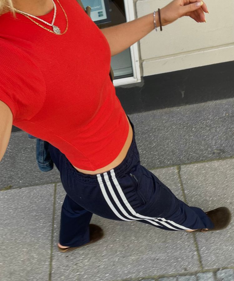 Street style photography of a person wearing wide-leg track pants with a stripe detail and an oversized blazer.