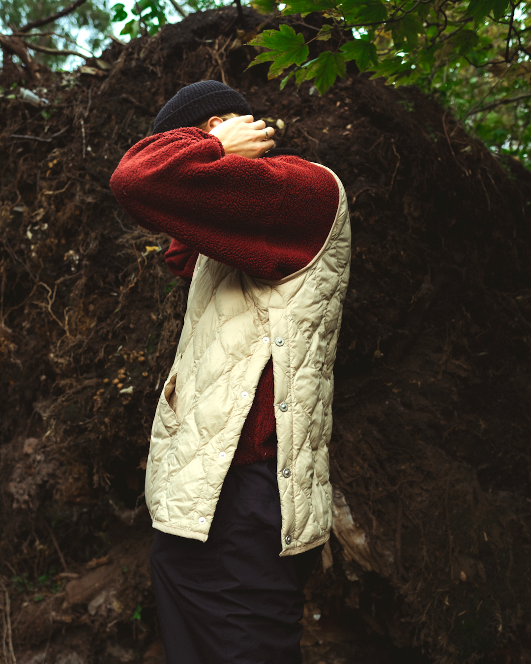 A man wearing a red fleece-lined quilted vest over a maroon sweater in an outdoor setting.