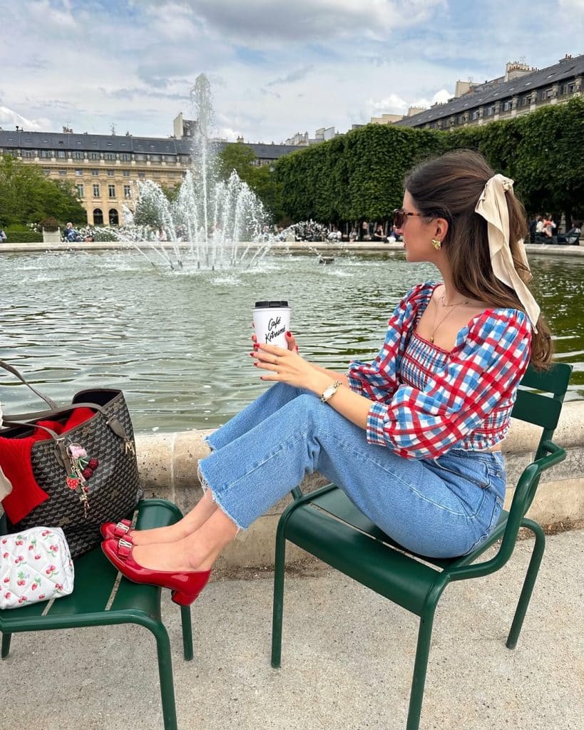 A woman in a gingham top and cropped jeans featuring bright red ballet flats.