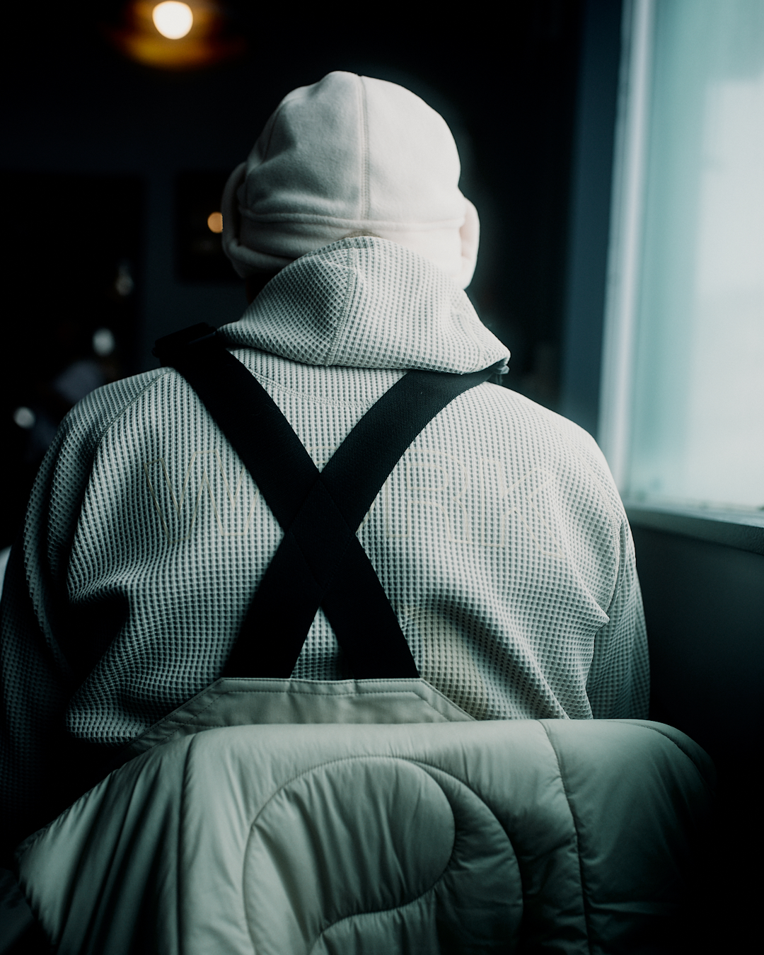 Close-up of a person wearing a textured waffle-knit hoodie and black suspenders.