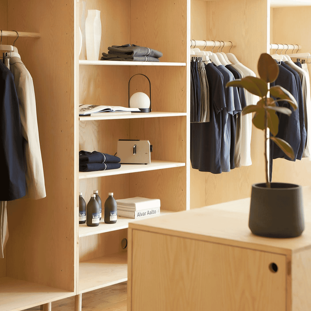 A minimalist wooden closet with neatly arranged shirts and sweaters.