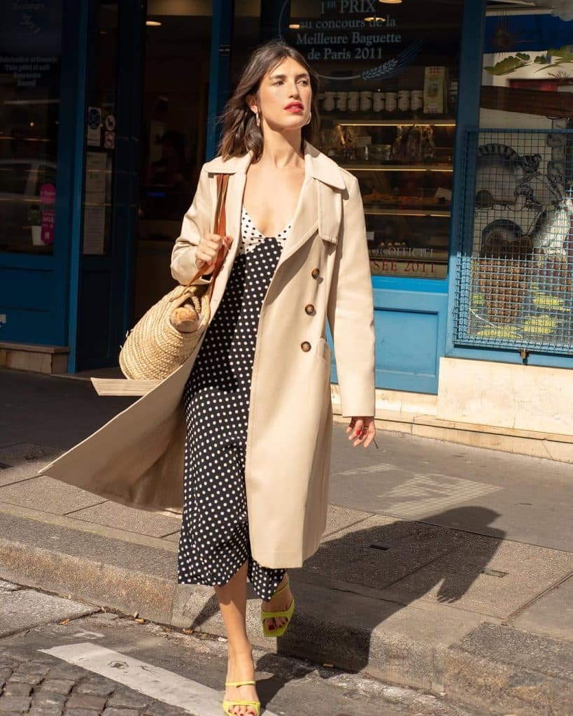 A woman in a romantic polka dot midi dress standing in a Parisian setting.